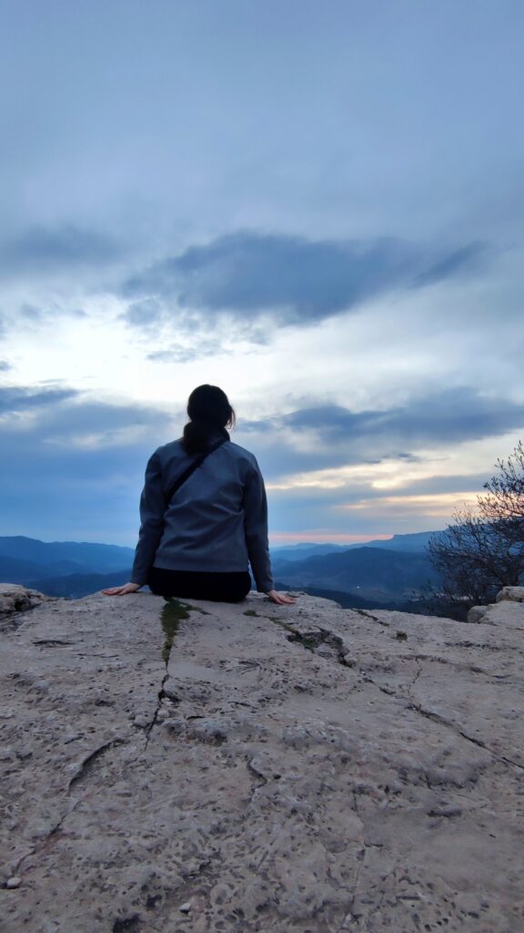Senderista sentada disfrutando del atardecer tras una ruta de montaña