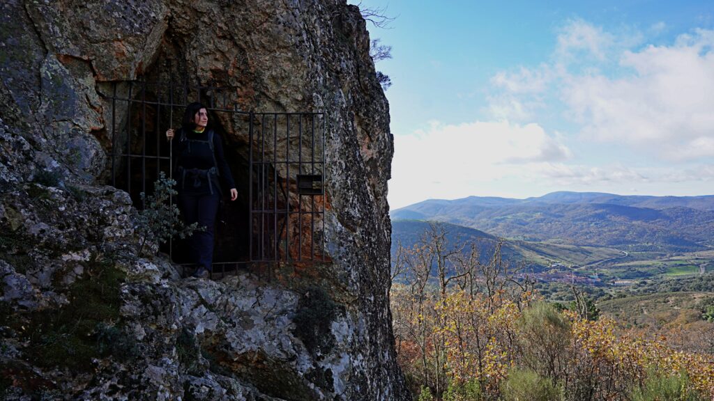 Persona saliendo de una cueva hacia un paisaje natural abierto