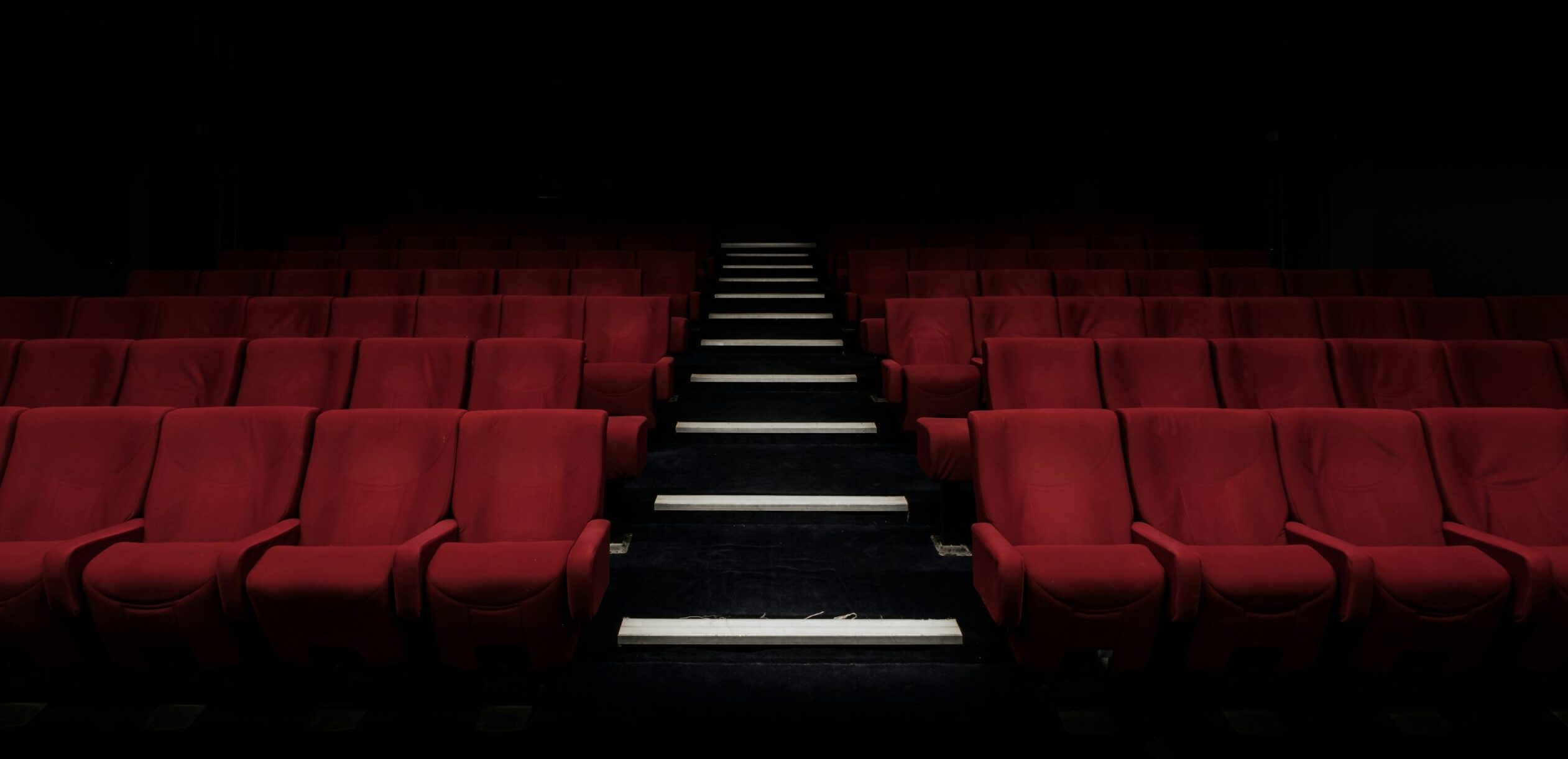 Sala de cine vacía con butacas rojas, símbolo de películas que remueven conciencias y no siempre llegan al gran público.