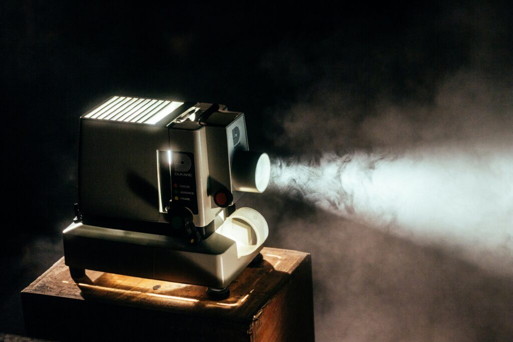 Proyector de cine antiguo encendido en la oscuridad, símbolo de películas que sacan a la luz verdades ocultas.