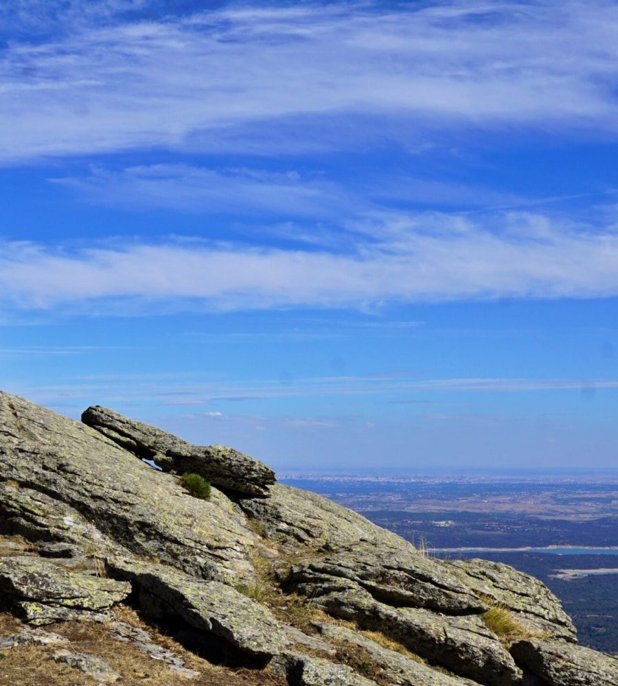 Excursionista junto a la cruz del Mirador de los Poetas en la cima de la sierra, con el embalse al fondo.