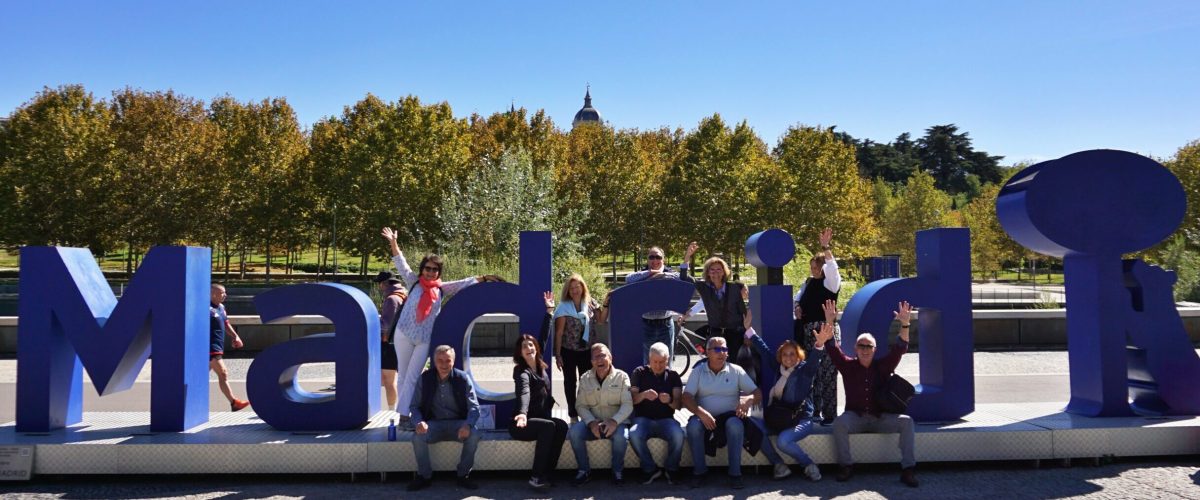 Grupo posando con entusiasmo junto a las letras gigantes de Madrid.