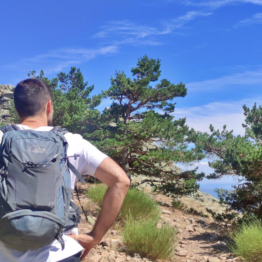 Senderista con mochila observando un vértice geodésico en la montaña.