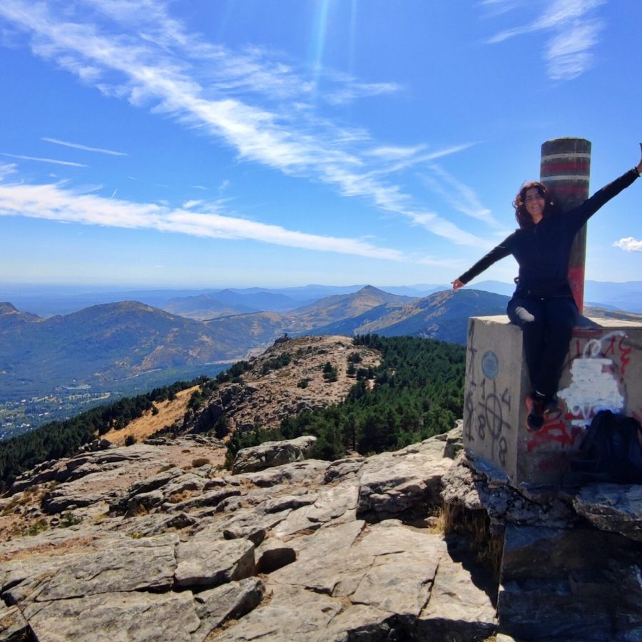 Persona celebrando en lo alto del vértice geodésico con vistas a la sierra.