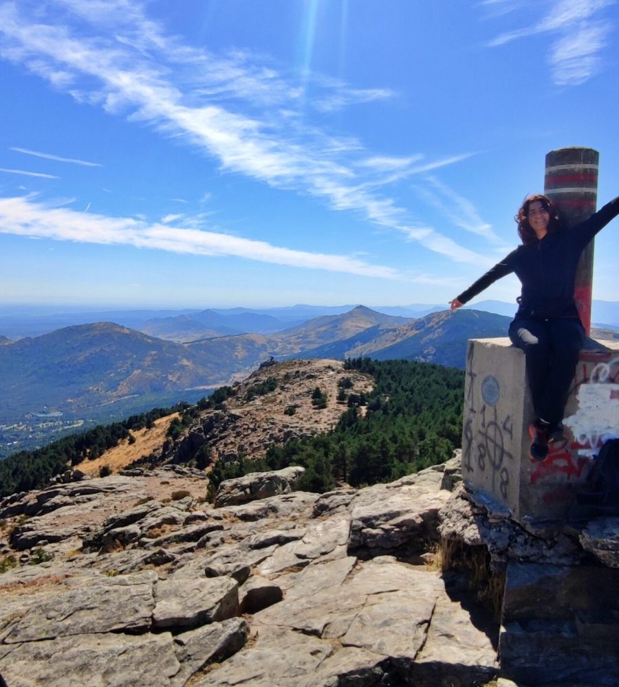 Persona celebrando en lo alto del vértice geodésico con vistas a la sierra.