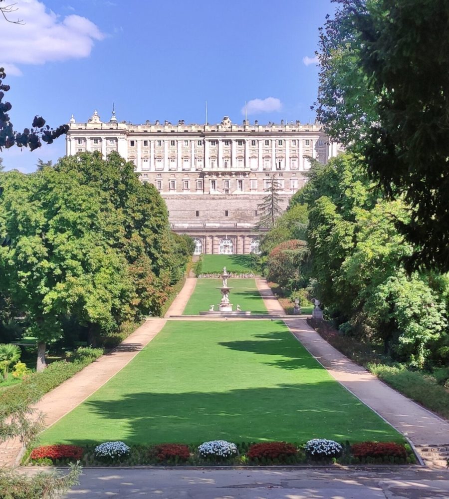 Vista del Palacio Real desde los Jardines del Campo del Moro, enmarcado por árboles.